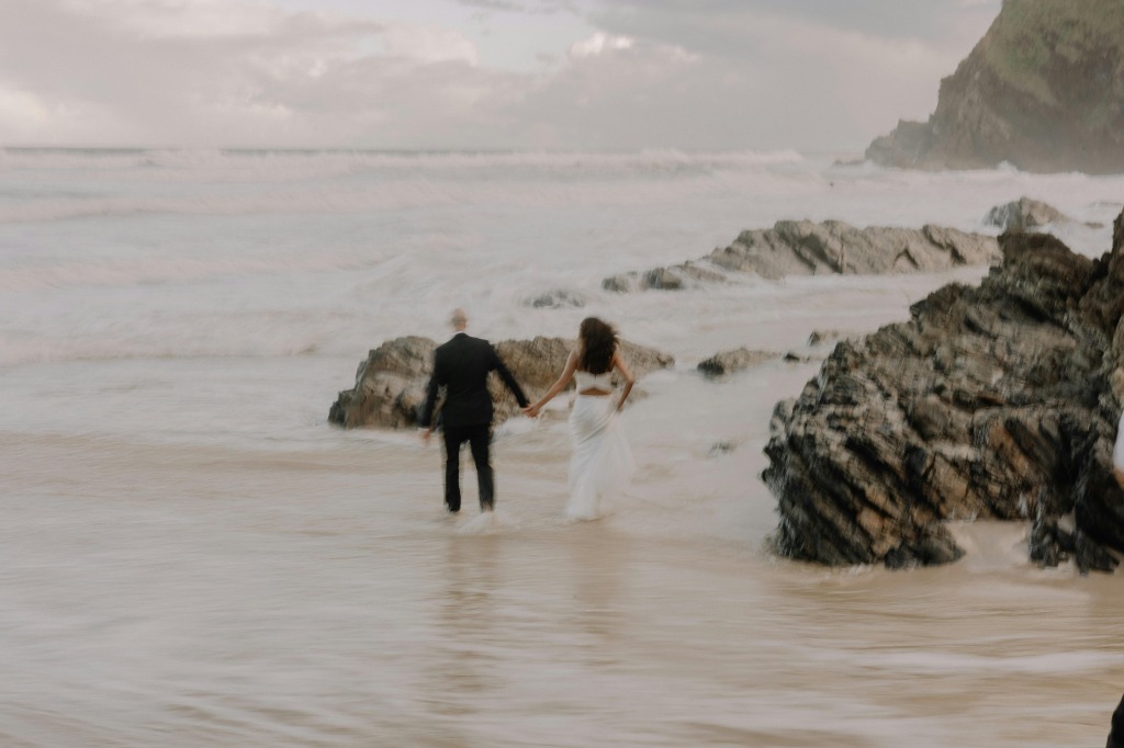 Couple walking into the ocean on the beach